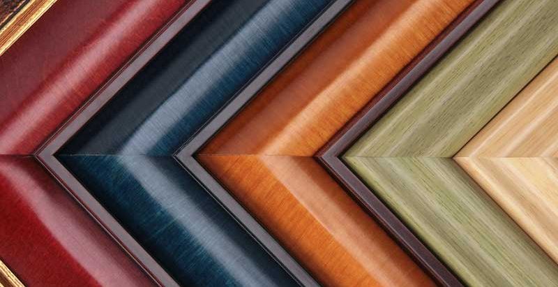Close-up of colorful frame moulding corner samples in red, blue, orange, green, and natural wood