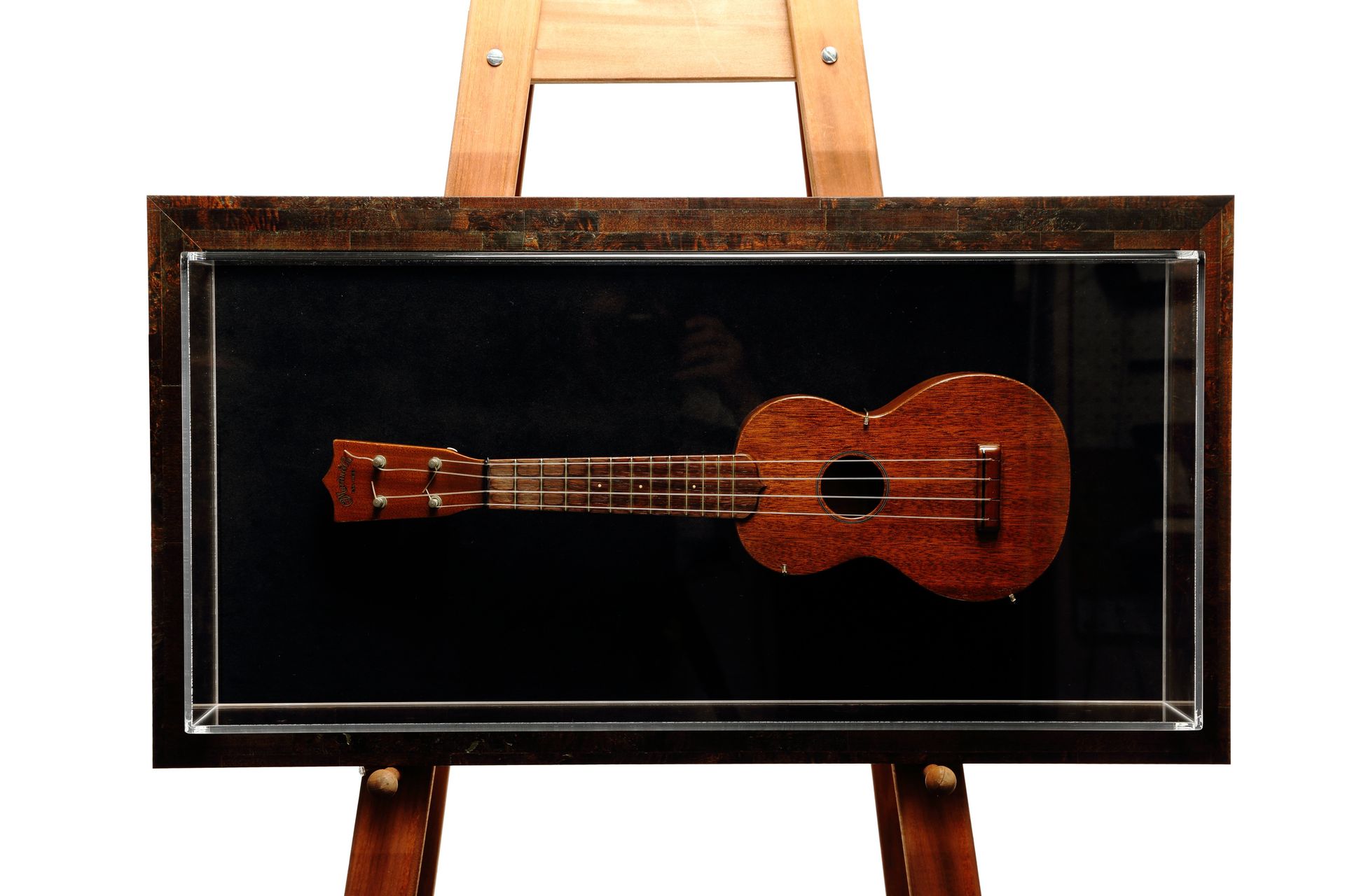 Vintage mahogany ukulele mounted in a deep acrylic-front shadow box frame
